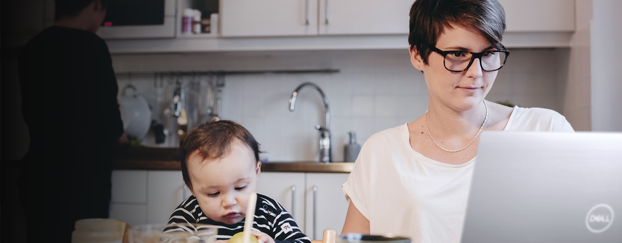 woman learning from home with her baby sitting next to her 